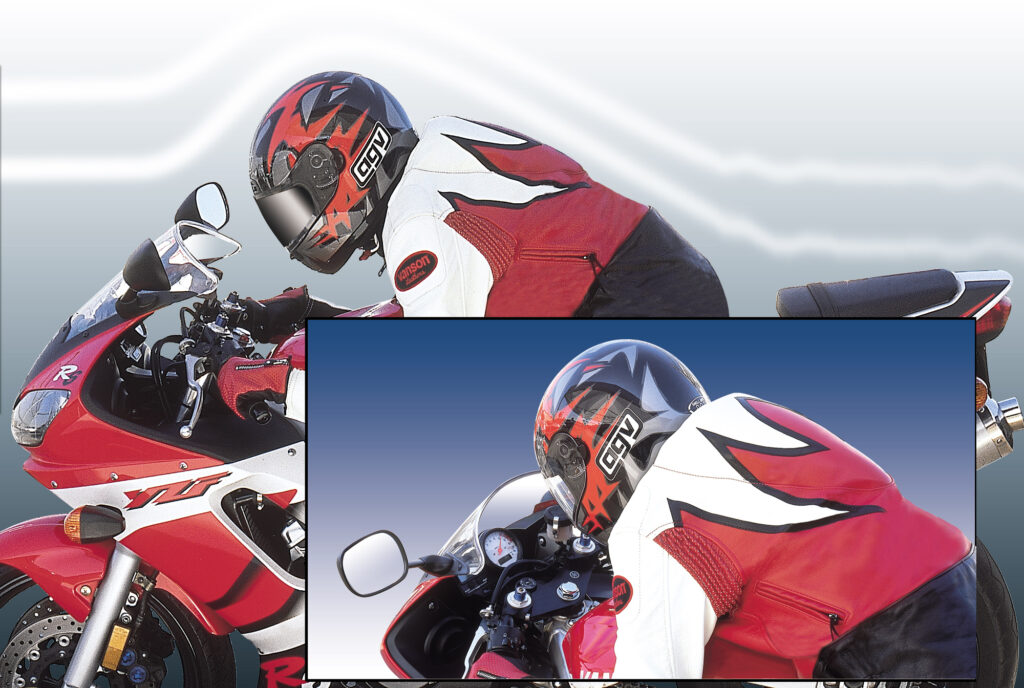 A motorcyclist in a red and white leather suit and helmet rides a red sportbike, focusing intently on the road ahead.