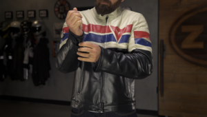 A man adjusts the cuff of a vintage-style motorcycle leather jacket, featuring bold red, white, and blue stripes.